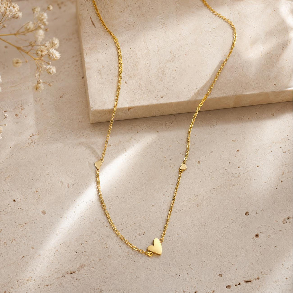 multi heart minimalist necklace with 3 hearts styled on neutral background flatlay style jewellery appealing to women