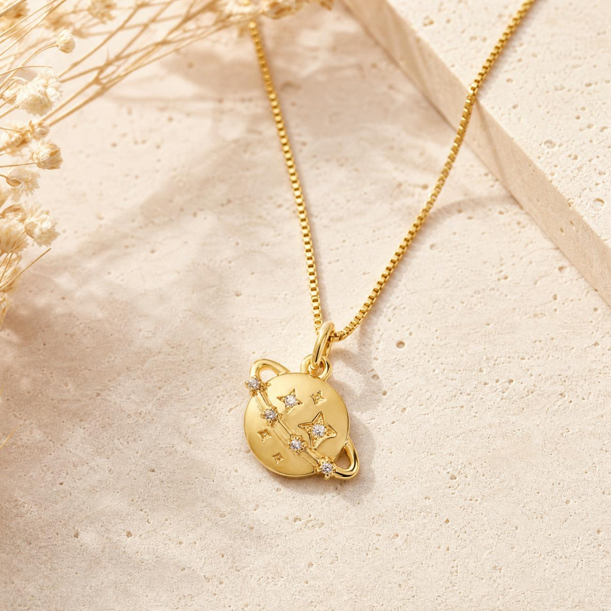gold plated planet pendant on box style chain styled on neutral background celestial jewellery appealing to women